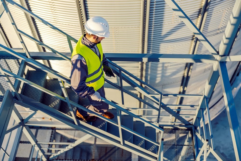 An,Industry,Worker,Descending,The,Stairs,On,Silo,With,Tablet
